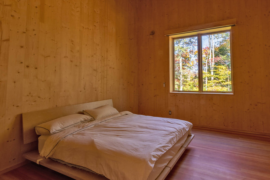 A secondary bedroom with wood flooring and wood paneled walls finished with Rubio Monocoat Oil Plus 2C.