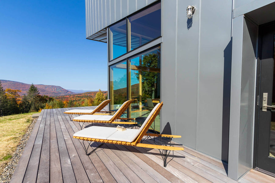 A wooden deck with three lounge chairs pictured.