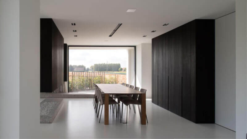 A modern dining room with dark wood ceiling height cabinets and a white floor.