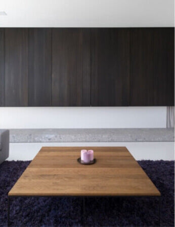 A brown wood coffee table and dark wood wall cabinets in a living room.