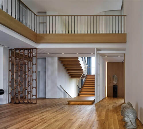 Natural looking hardwood floors with a staircase with accent lighting in a house with white walls.