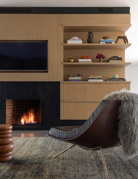Wood paneled built in unit with fireplace, television and open shelving.