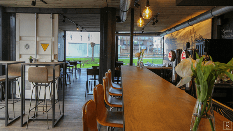 A oil finished bar-top inside of a shipping container restaurant.