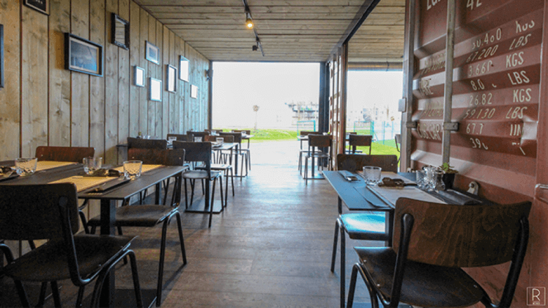 A restaurant patio area made from shipping containers with a wood floor.