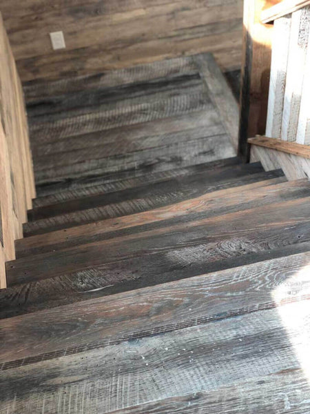 A view down a set of stairs that are make from skip and miss oak wood flooring.