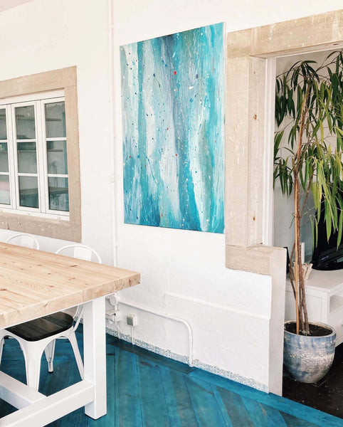 A wooden table sits atop a bright blue chevron floor in a surf lodge in Portugal.
