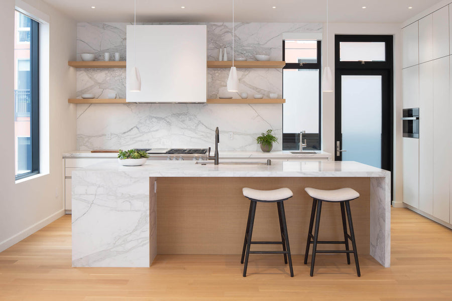 Light and clean kitchen with rift sawn white oak floors, marble island and backsplash, and floating shelving.
