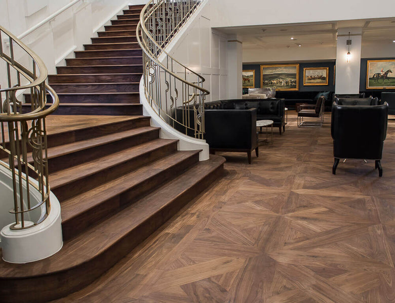 Beautiful wide walnut wood staircase with gold banisters.