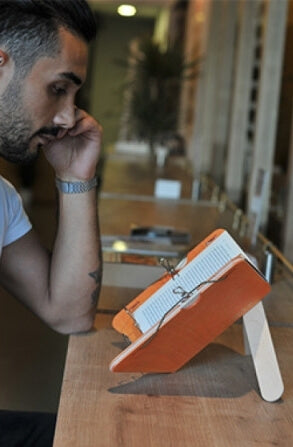 Man sitting on couch using a book saddle.