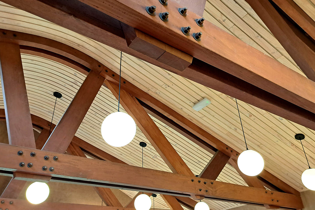 Close-up of curved timber ceiling slats and structural wood beams finished with Rubio Monocoat, showing the natural grain and joinery of the vaulted roof structure.