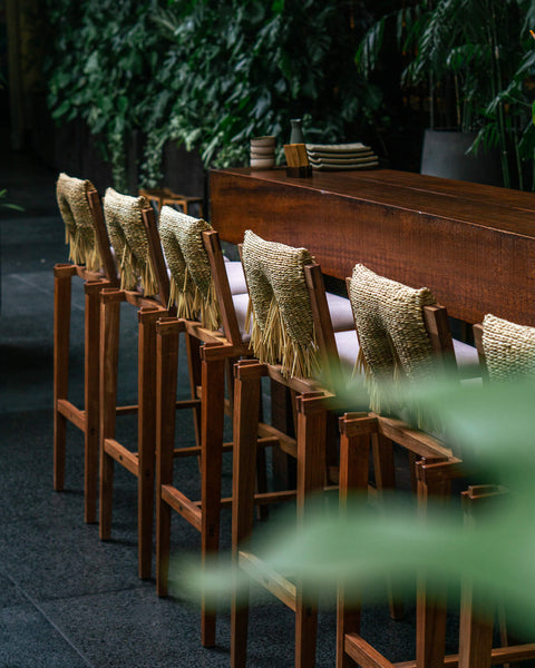 Several bar height chairs made from Cachimbo wood and finished with Oil Plus 2C "Pure" with natural fiber details on the back.