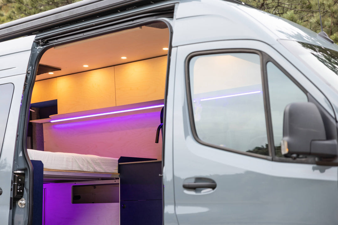Exterior of a camper van looking into the van where birch cabinetry finished with Rubio Monocoat Oil Plus 2C hardwax oil can be seen.