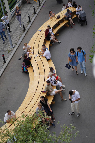 Multiple people sitting at a large, winding picnic table crafted from spruce and finished with Rubio Monocoat DuroGrit "Grassland Beige".