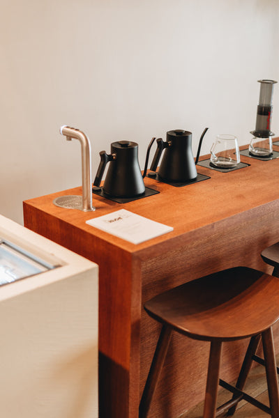 Two water kettles and two mugs sit on an oak veneered table finished with Rubio Monocoat.