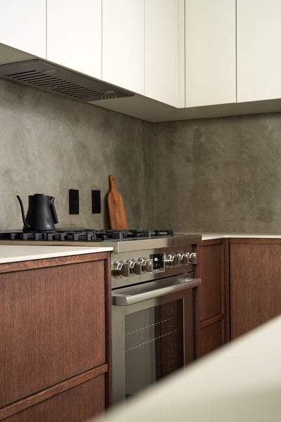 Upper white cabinets are contrasted by lower brown cabinets with a stove in a modern kitchen.