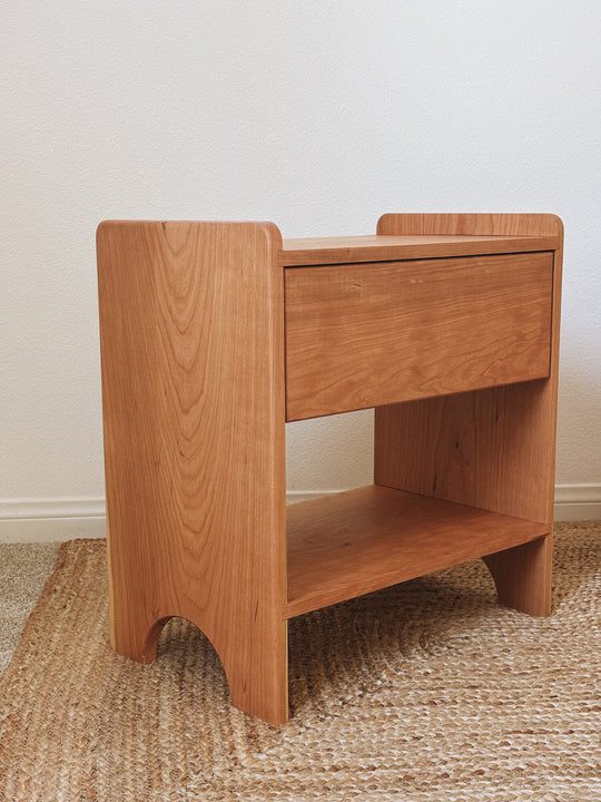 Front view of solid cherry wood nightstand with push-to-open drawer and arched leg detail, natural single coat Rubio Monocoat Pure stain and .
