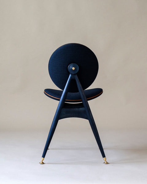 A blue, wood dining chair with brass, leather and fabric accents. 