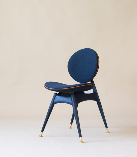 A modern  chair with a blue hue and circle chair back and seat. 