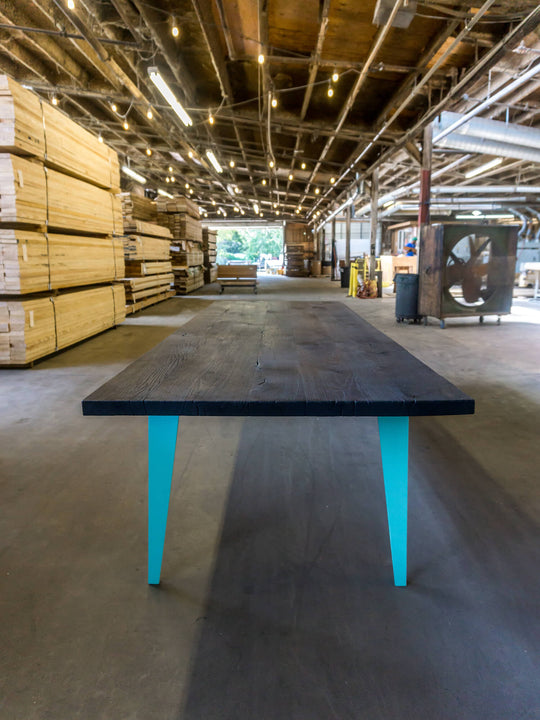A dining table with a charred look finished with Rubio Monocoat Oil Plus 2C and blue metal legs.