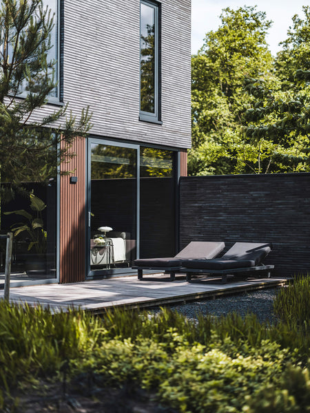 An outside lounge area with a background of exterior wood cladding finished with DuroGrit Bison Brown.