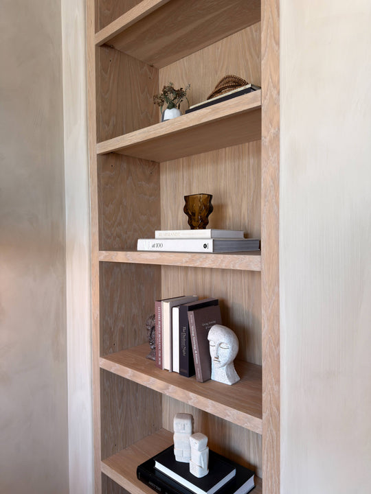 Built-in white oak bookshelf finished with Rubio Monocoat Oil Plus 2C Natural, styled with ceramic sculptures, art books, and dried florals.