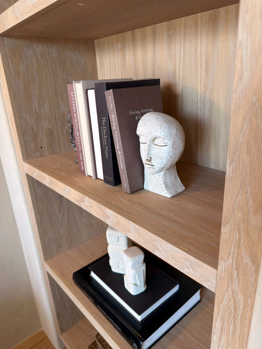 Detail of white oak shelving in Rubio Monocoat Oil Plus 2C Natural, showing natural grain beneath a curated stack of books and a carved head sculpture.