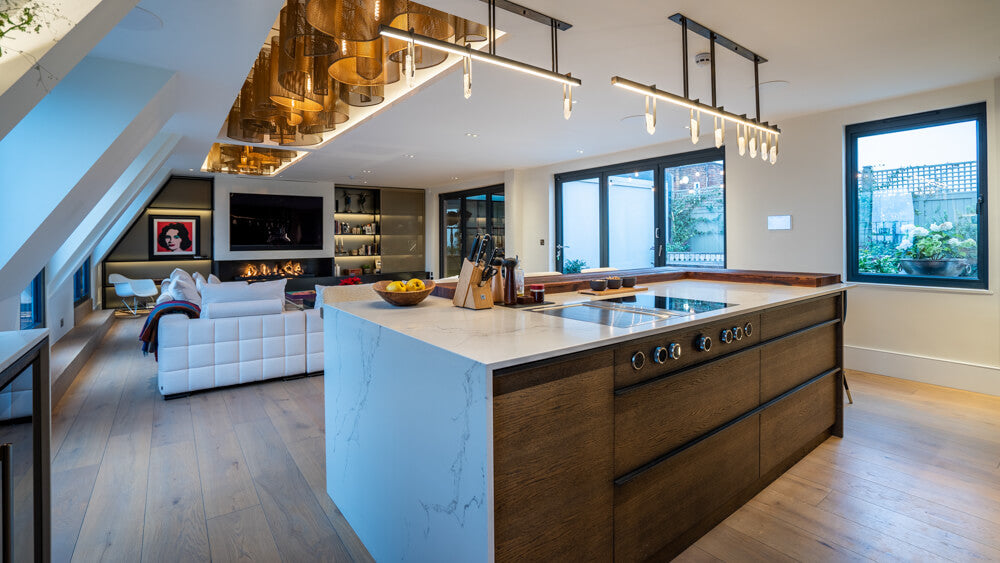 A modern kitchen island with cabinets made from oak looking into a lavish living room. 