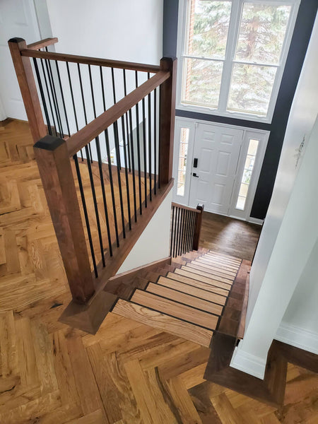 Herringbone floor looking down a custom staircase crafted from a variety of wood species.