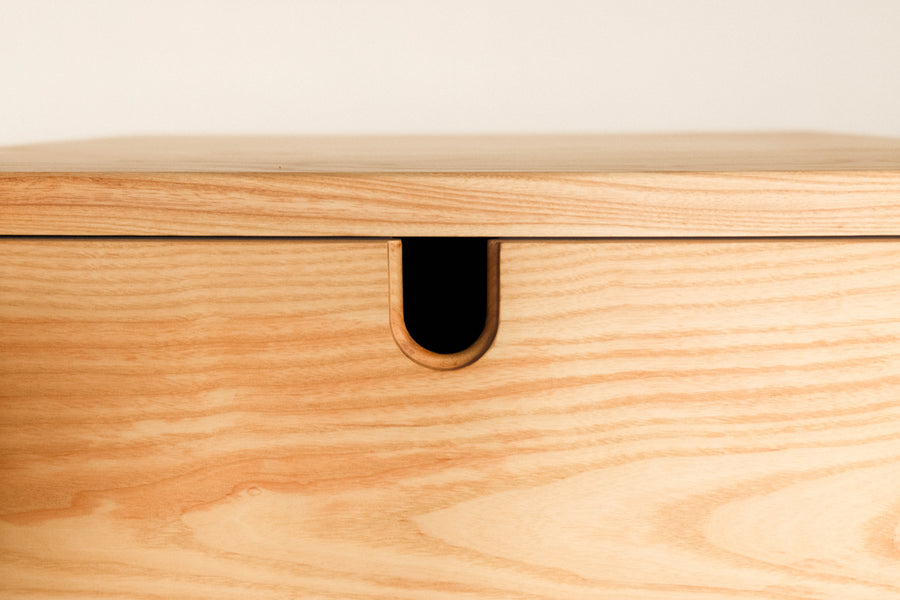 A tight shot of an ash nightstand with an integrated finger pull. 