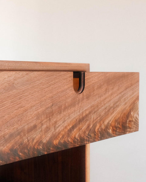 A close up of a side table's drawer with an integrated drawer pull. 