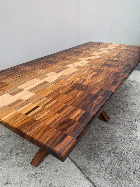A dining table comprised of seven different species of wood, creating an ombre pattern.