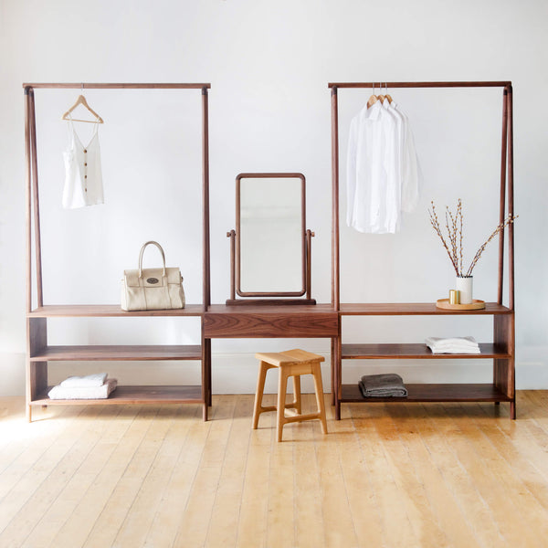 Two open wardrobe racks with a center vanity portion. Various items are displayed on the wardrobe rack. 