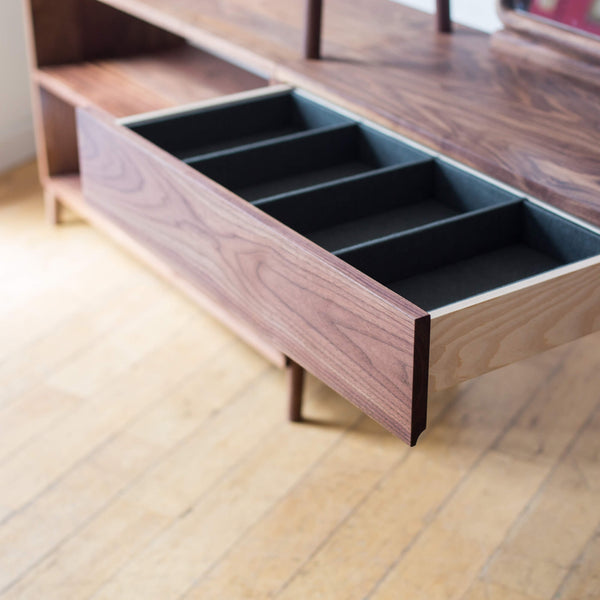 Open walnut drawer in the vanity section of an open walnut wardrobe rack. 