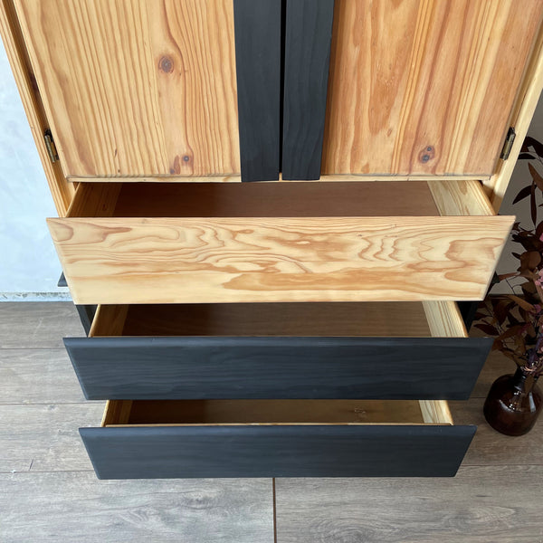 A two-toned pine armoire with it's three drawers slightly ajar.