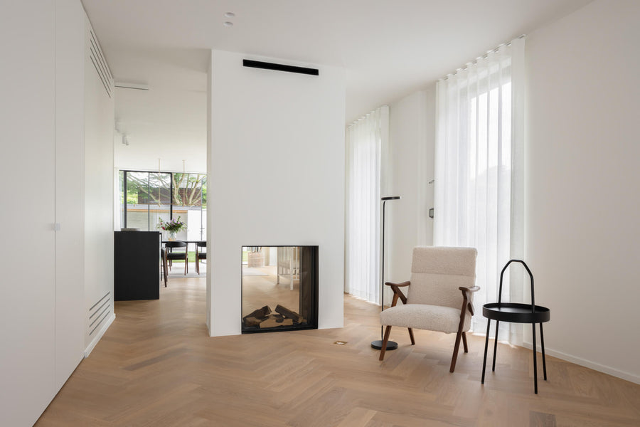 A plaster double sided fireplace in a living room with beautiful light-colored oak hardwood flooring.