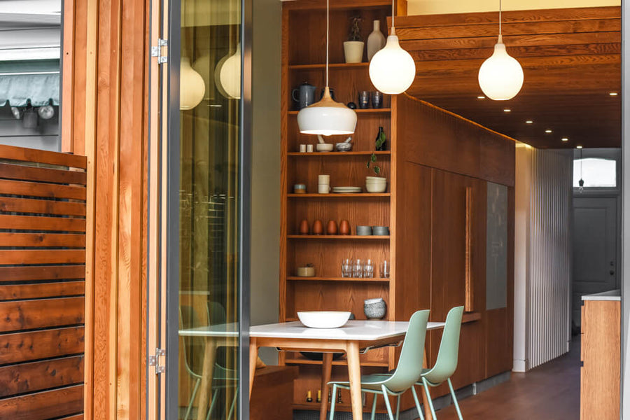 Looking from the outside in, a dining area and galley kitchen with many wood elements colored and protected with a hardwax oil wood finish.