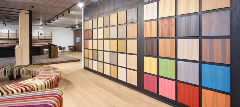 A wall showing color tiles of the Rubio Monocoat interior and exterior colors with a bench and other decor in the background.
