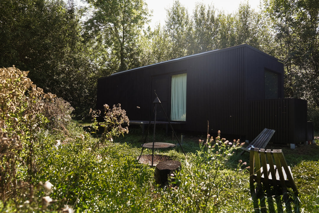 The foreground of the image features a firepit while the black Slow Cabin is in the background.