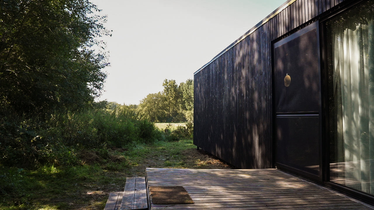 A cabin with vertical pine siding finished with DuroGrit in the color "Saddle Black".
