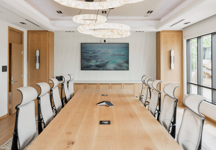 An elegant boardroom with a white oak table, cabinetry, and unique lighting. 