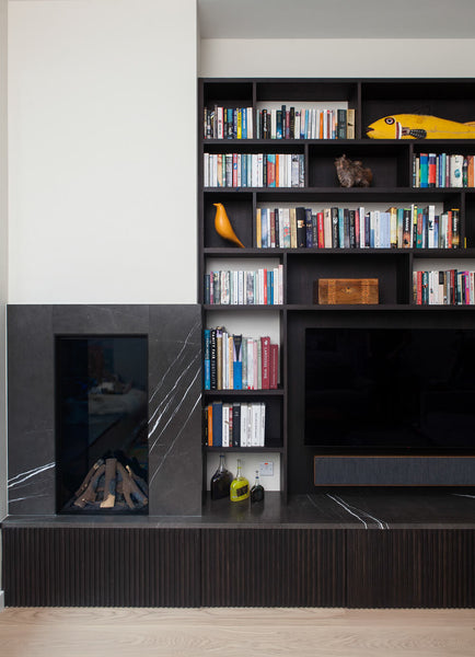 A very dark brown media built-in featuring Rubio Monocoat products, featuring dark grey marble stone.
