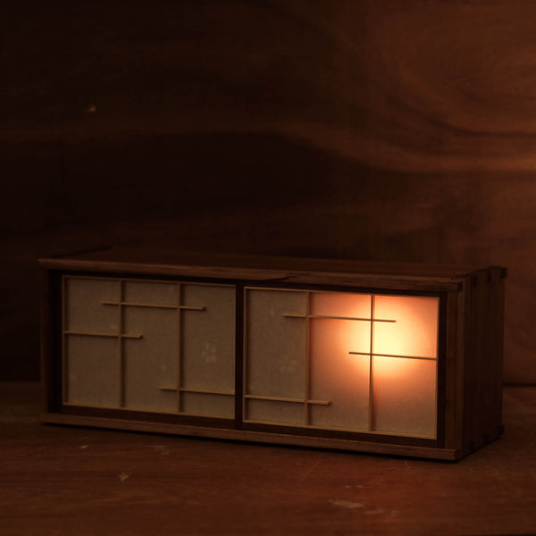 A tea cabinet made from wood with an interior light designed to resemble the silhouette of the moon. 