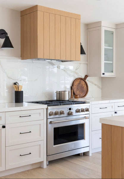 A bright kitchen with a vertical paneled white oak range hood finished with a hardwax oil wood finish.