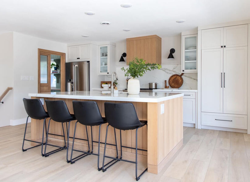 A modern yet inviting kitchen with a range hood, island, and pantry doors made from white oak and finished with Rubio Monocoat hardwax oil wood finish.