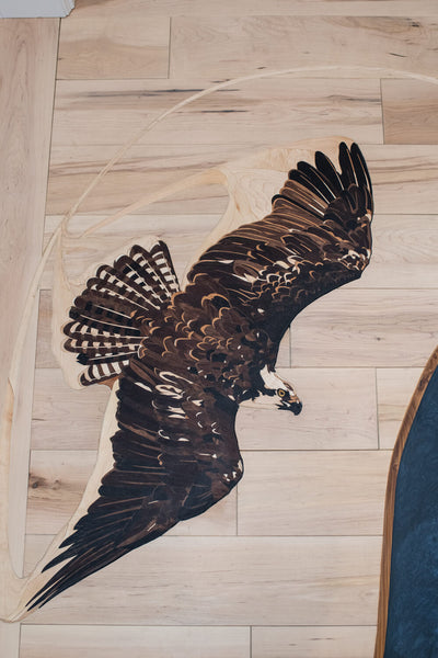 Osprey wood floor inlay in a hardwood floor.