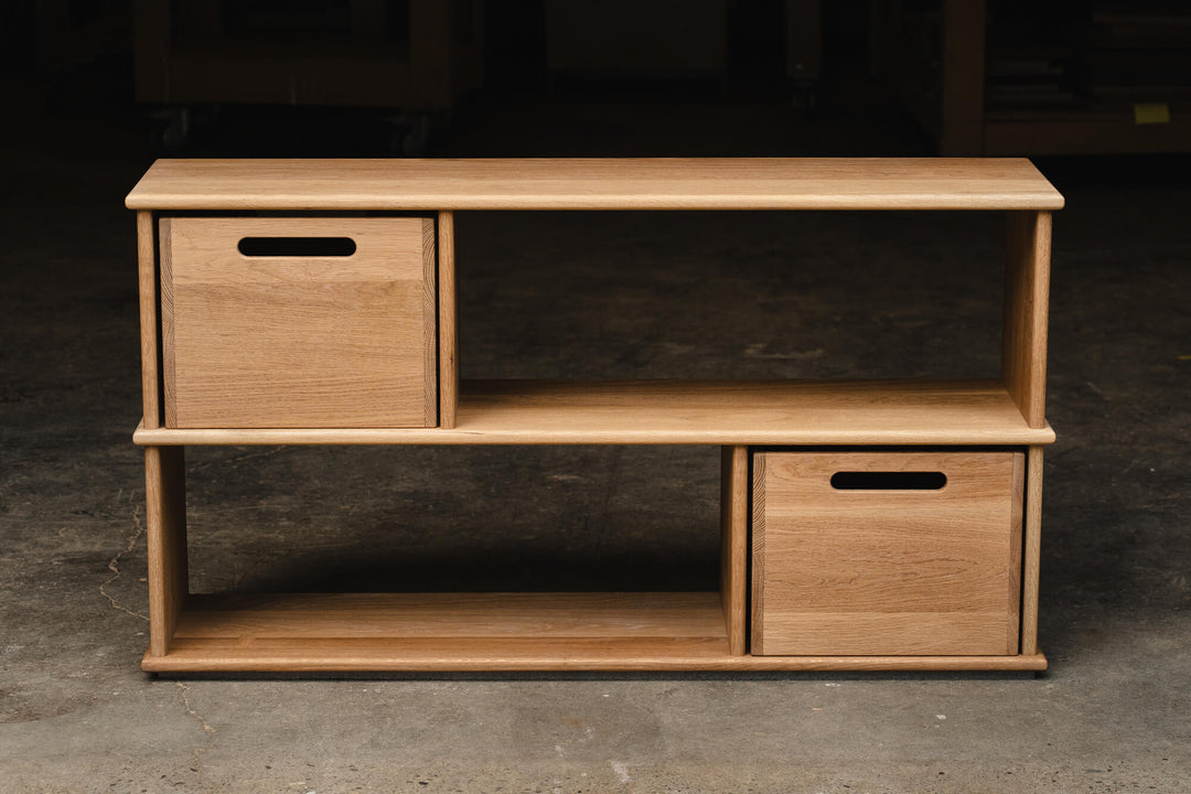 Front-facing view of a two-tier white oak bookcase with open shelving and two removable storage cubes, featuring a Rubio Monocoat Dunes hardwax oil finish.