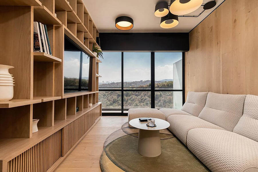 A view looking into a living room with white oak built-ins to the left and a comfortable sofa in front of white oak paneling to the right. 