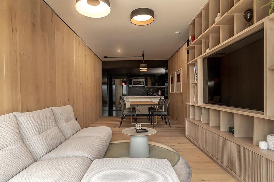 A view of a modern living room with a sofa on the left and white oak built-in entertainment center to the right. 