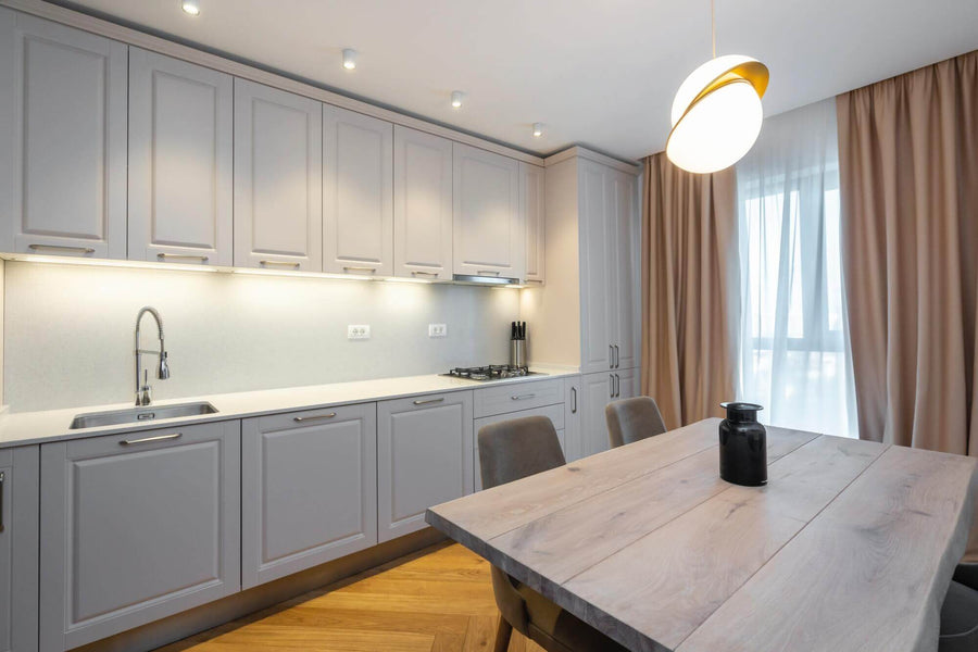 Kitchen with white cabinets, live edge table, and herringbone wood flooring.