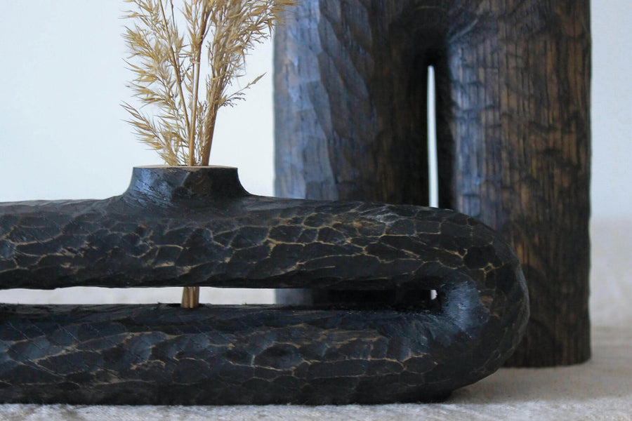 An oblong hand carved wooden vase.